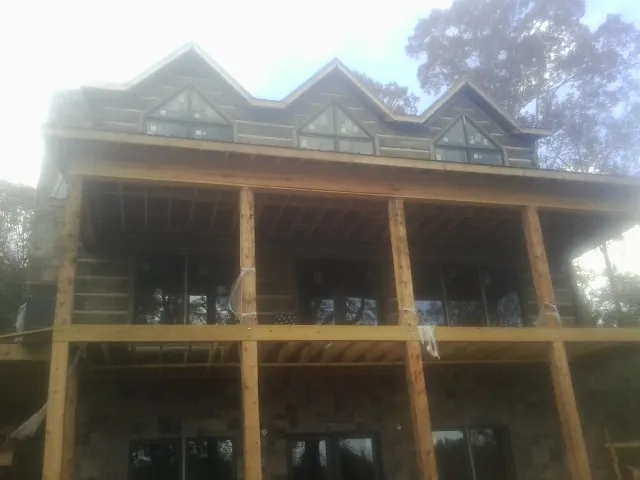Dormers and porch framing on a large log home under construction — Roof Coating work by our crew in Springville