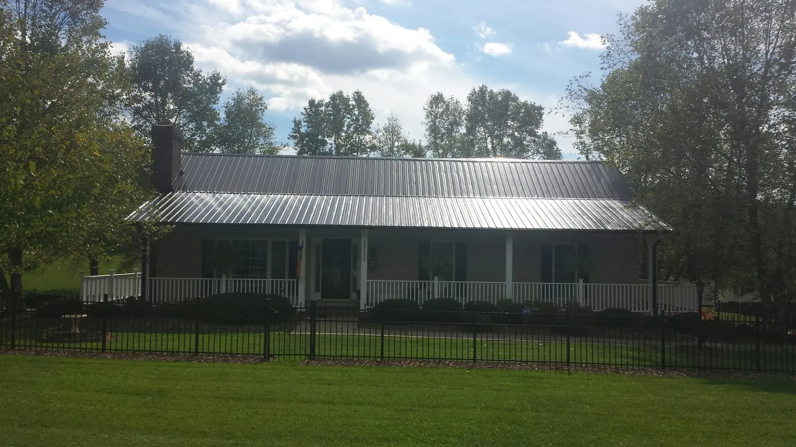Gray metal roof on a brick ranch with a full width front porch — Gutter Guard Installation work by our crew in Springville